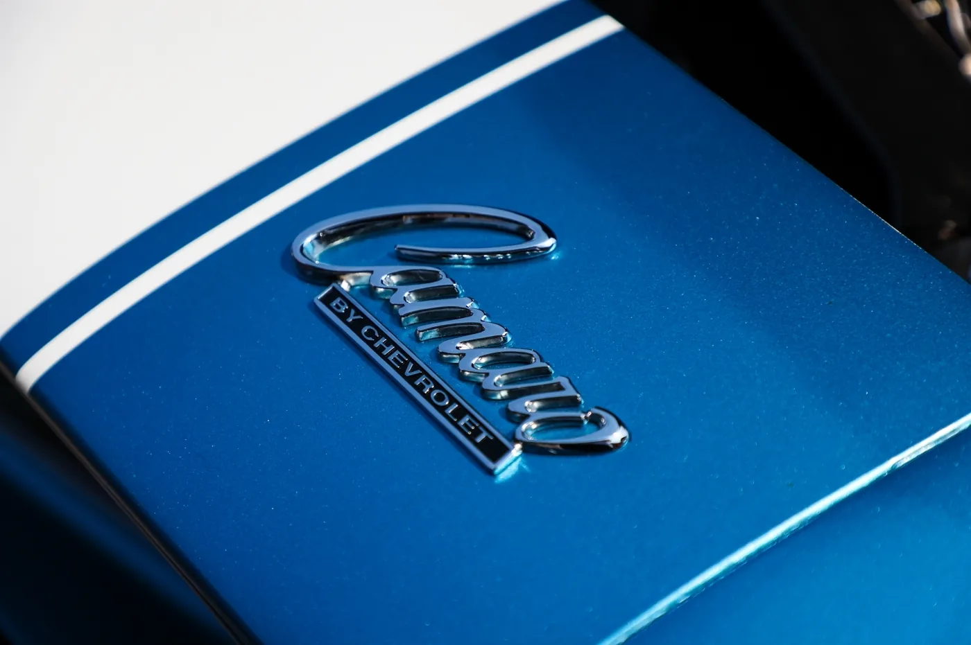 Chrome script badge on a blue hood beside a white racing stripe