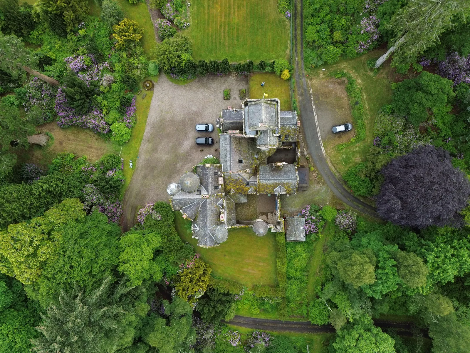 Top-down aerial of a stone estate surrounded by gardens and woodland