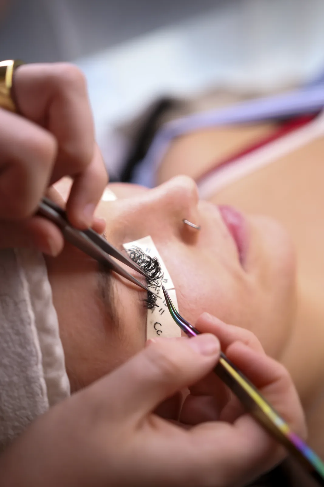 Close-up of lash extensions being applied with tweezers