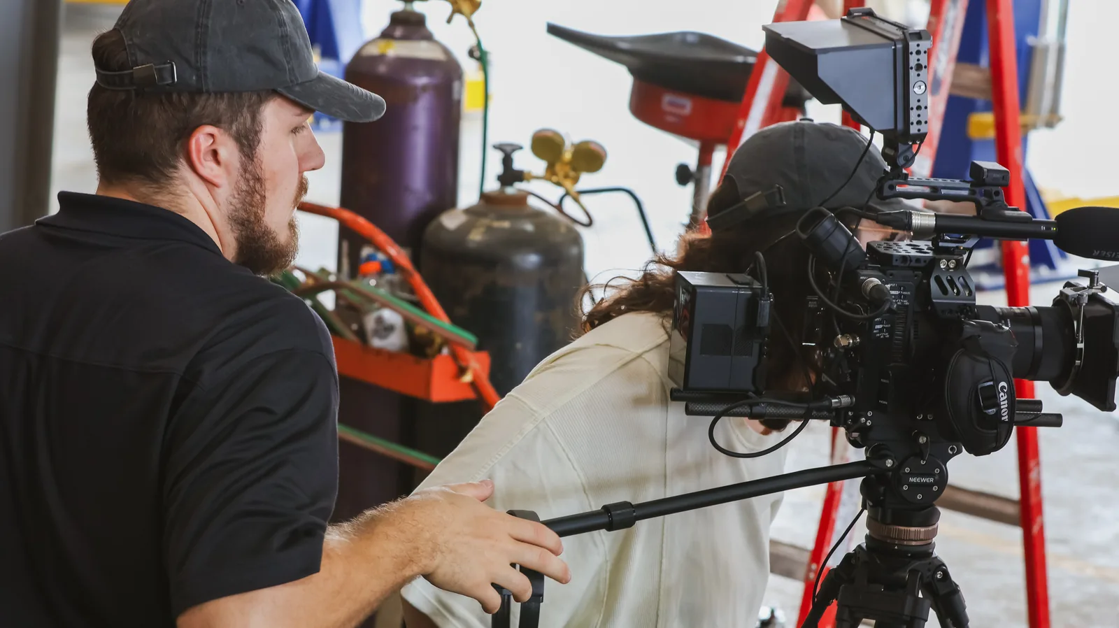 Two crew members working a tripod-mounted cinema camera and boom