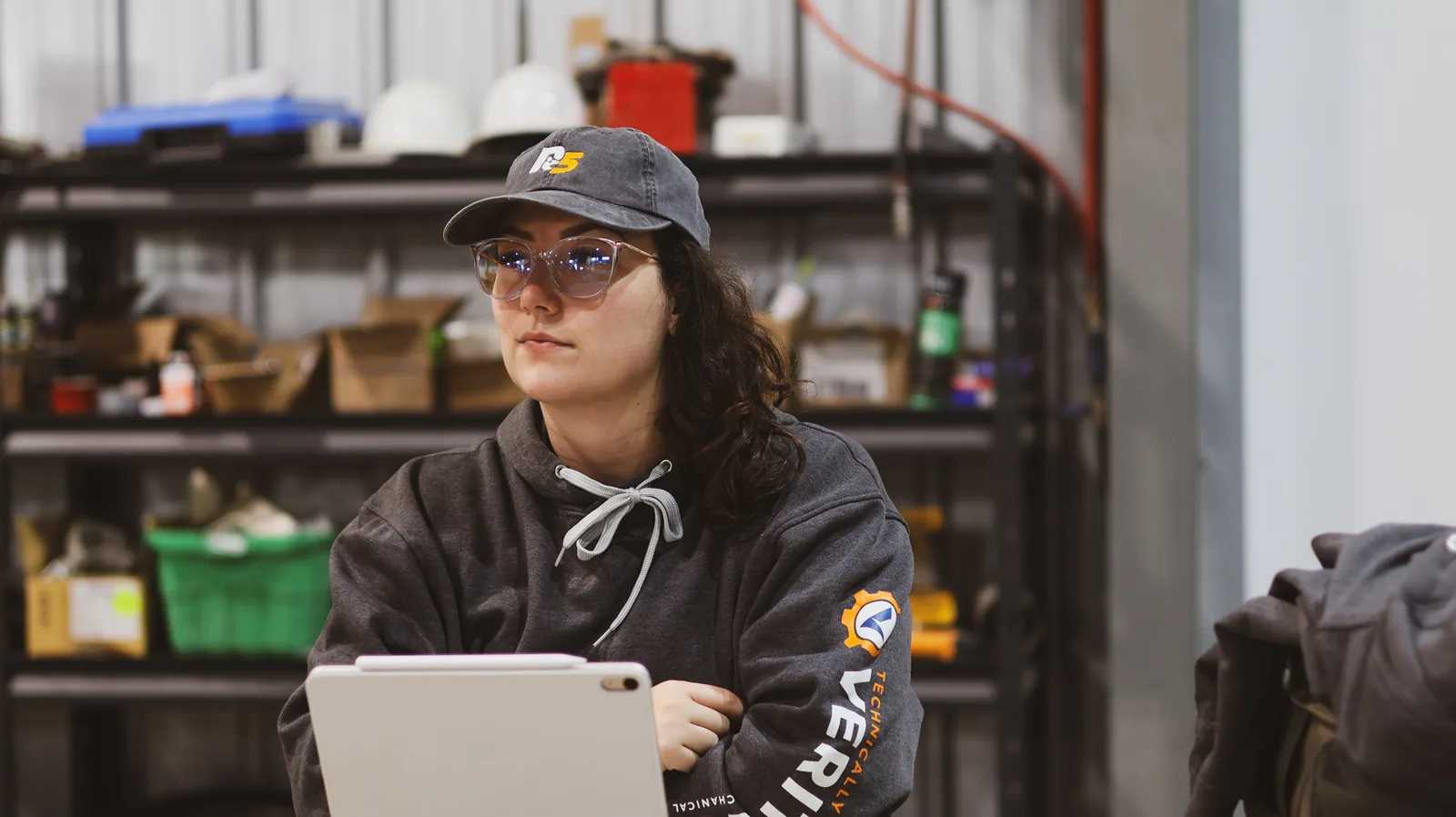 Crew member in a Runway 5 cap reviewing notes on a tablet in a mechanical shop