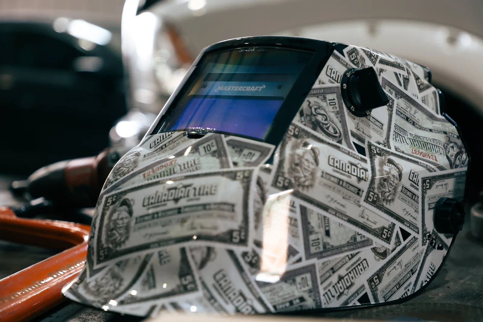 Patterned welding helmet resting on a workbench beside tools