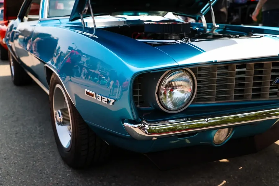Front quarter of a blue classic muscle car with a 327 fender badge at a car show