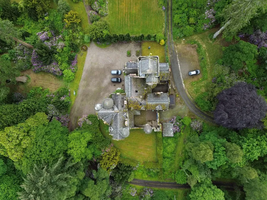 Top-down aerial of a stone estate surrounded by gardens and woodland